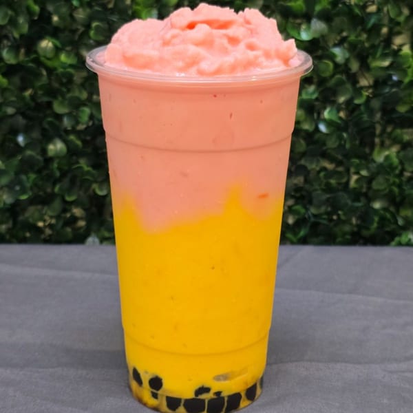 A vibrant two-toned drink with pink slush on top, yellow liquid in the middle, and boba pearls at the bottom.
