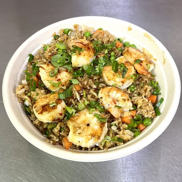 Shrimp fried rice with peas, carrots, green onions, and cilantro in a white bowl.